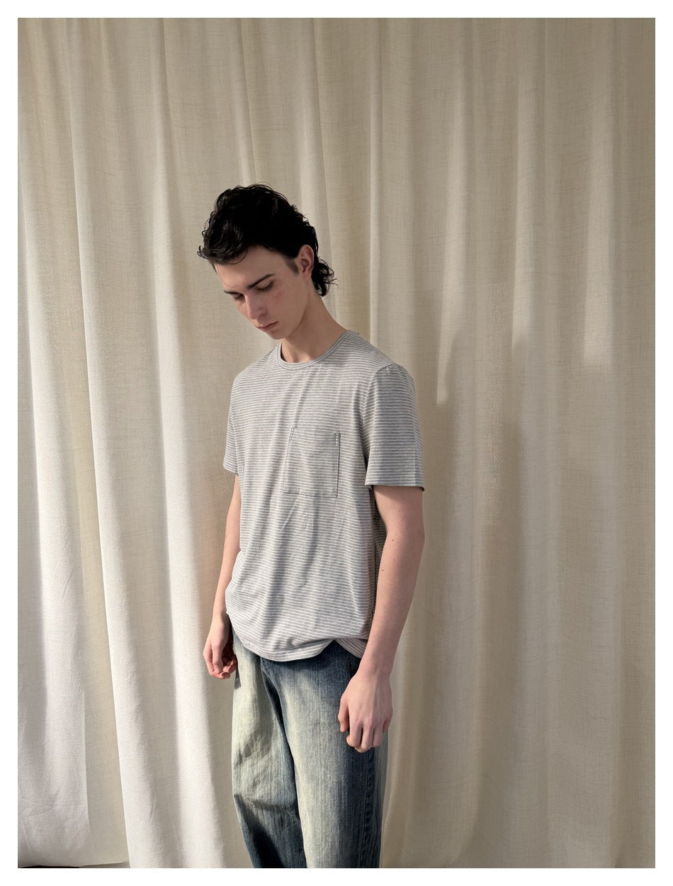 Model in a gray finely striped crew-neck T-shirt with a chest pocket, shown at an angle.