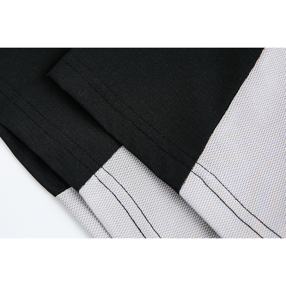Close-up of black and light gray T-shirt panels, seams, and double-stitched hems.