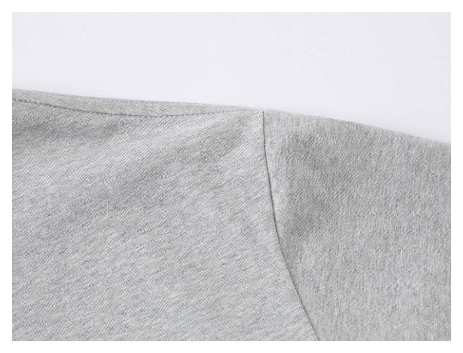 Close-up of the shoulder seam and sleeve construction on a heather gray T-shirt.