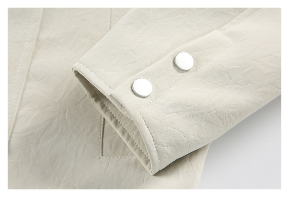 Close-up of an ivory jacket sleeve cuff with two large silver snaps.