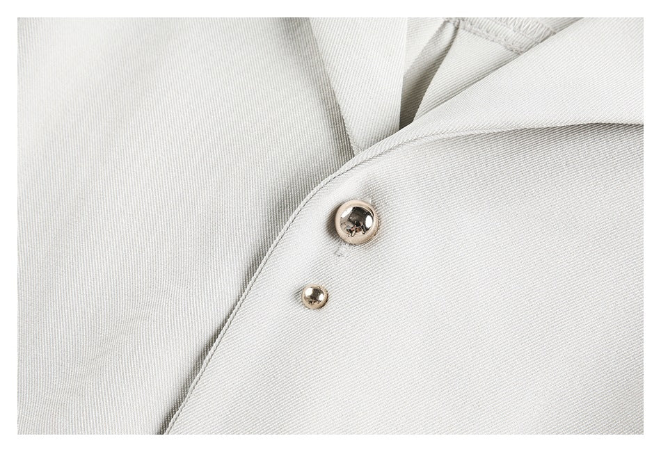 Close-up of the white tunic's fabric and two shiny metal buttons.