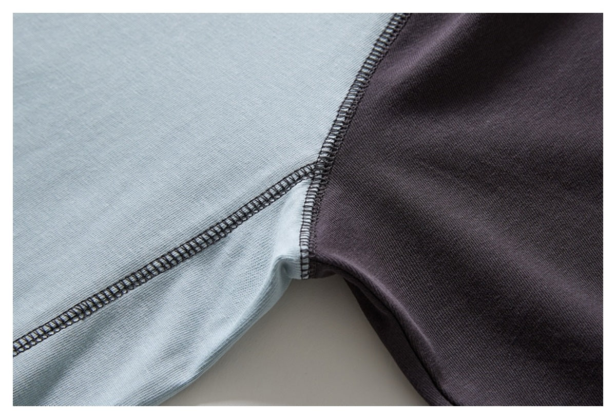 Close-up of pale blue and charcoal fabric panels joined with dark overlock stitching.