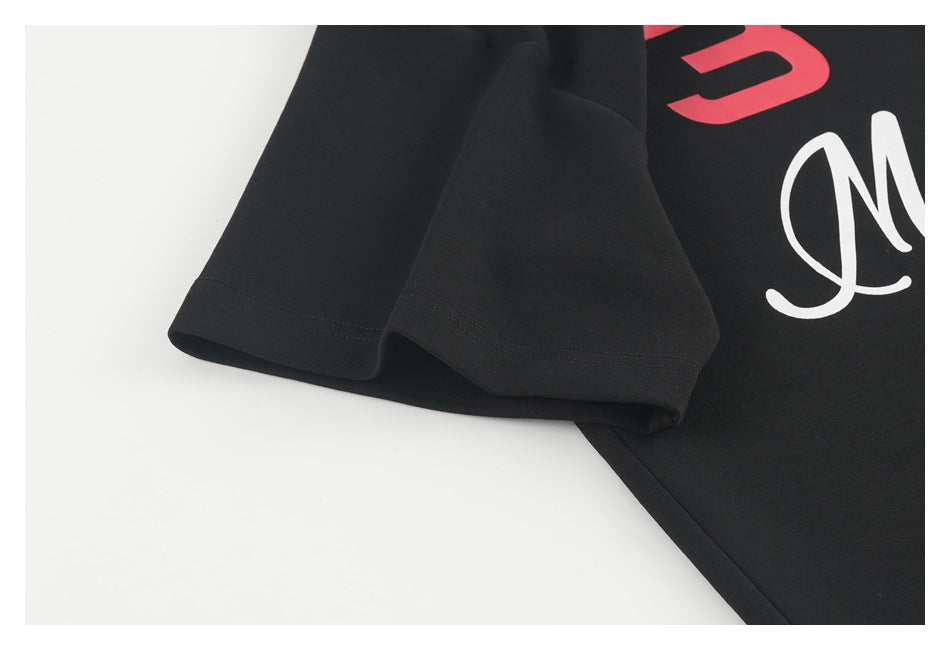 Close-up of a black short sleeve and partial red and white lettering printed on the garment.