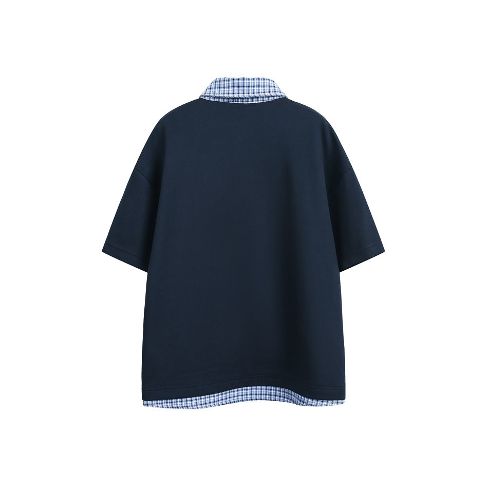 Back view of a dark navy short-sleeve top with a blue plaid collar and matching plaid hem trim.