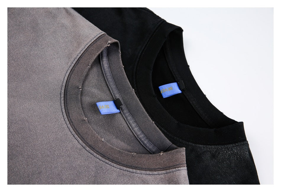 Close-up of gray and black crew-neck T-shirts showing their ribbed collars and inner labels.