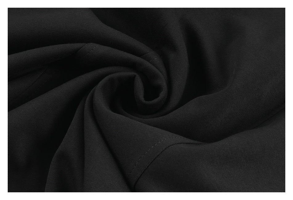 Close-up of black fabric draped in soft folds, showing its fine surface texture and stitching.