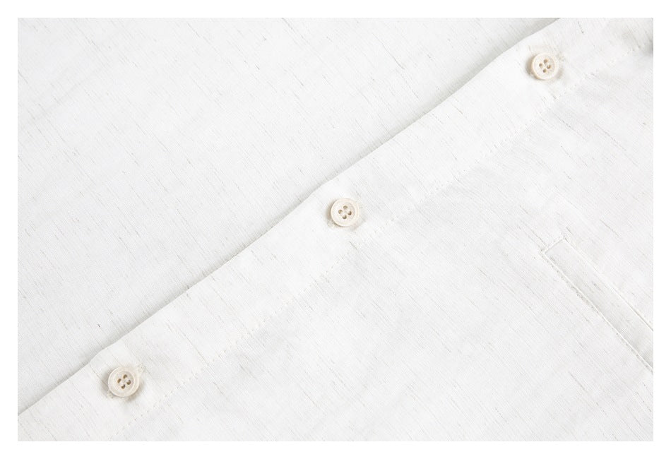 Close-up of an off-white shirt showing its button placket and chest pocket opening.
