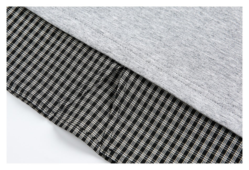 Close-up of heather gray fabric overlapping black-and-white checked fabric with visible stitching.