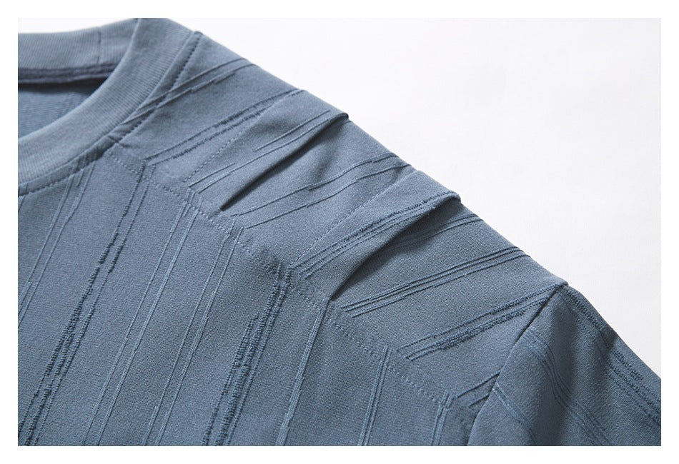 Close-up of a blue-gray top showing its round neckline, shoulder, and raised vertical stripe texture.