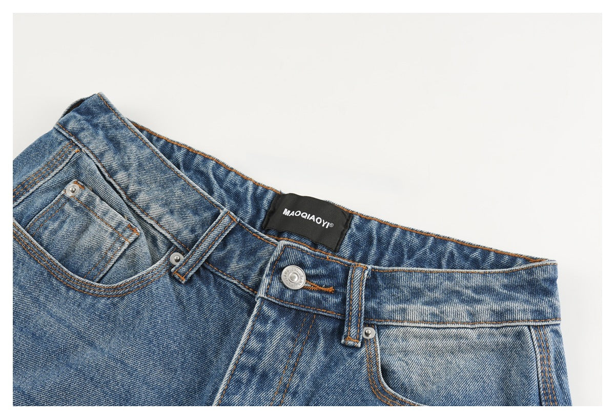 Close-up of the waistband, button, belt loops, and front pockets of blue denim shorts.