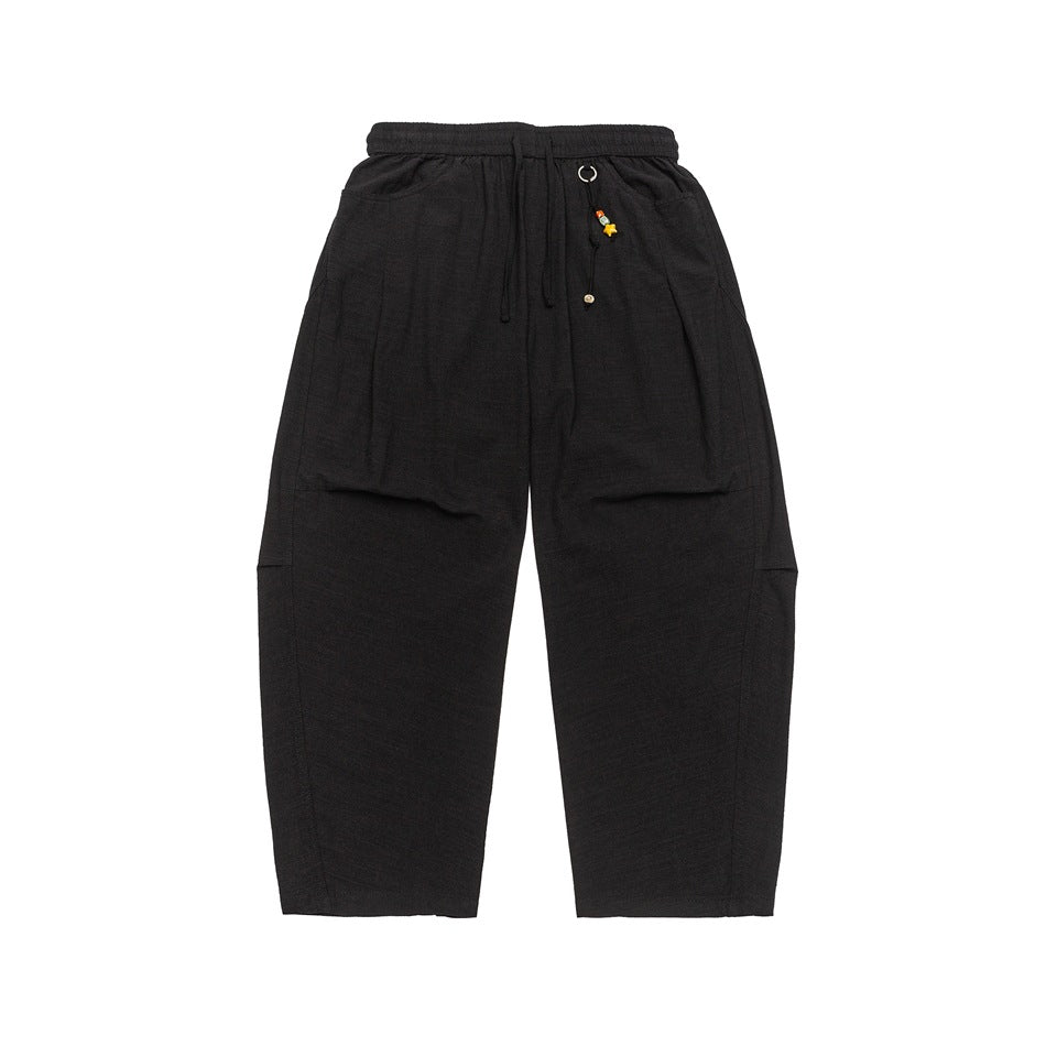 Black wide-leg drawstring pants with side pockets and a bead charm, flat lay front view