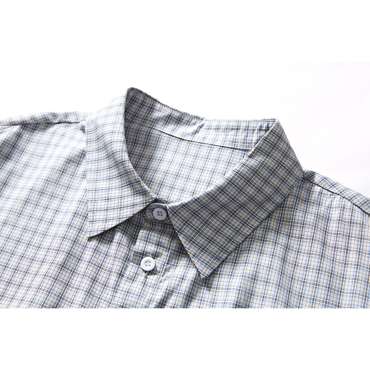 Close-up of a pointed collar and buttons on a light blue, gray, and tan plaid shirt.