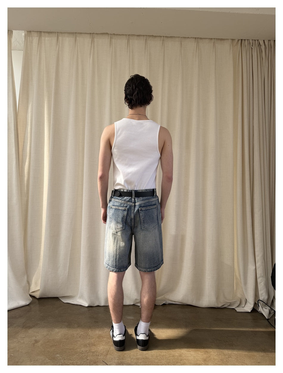 Back view of a man wearing faded blue denim shorts with two rear pockets and a black belt.