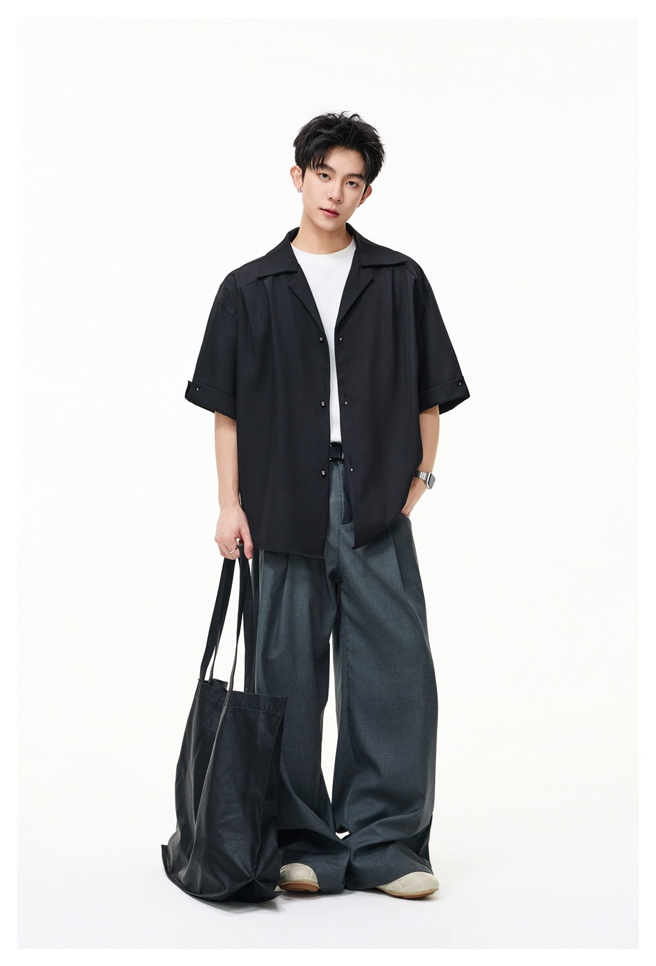 Full-length model wearing an oversized black short-sleeve button-up shirt with wide-leg gray trousers.