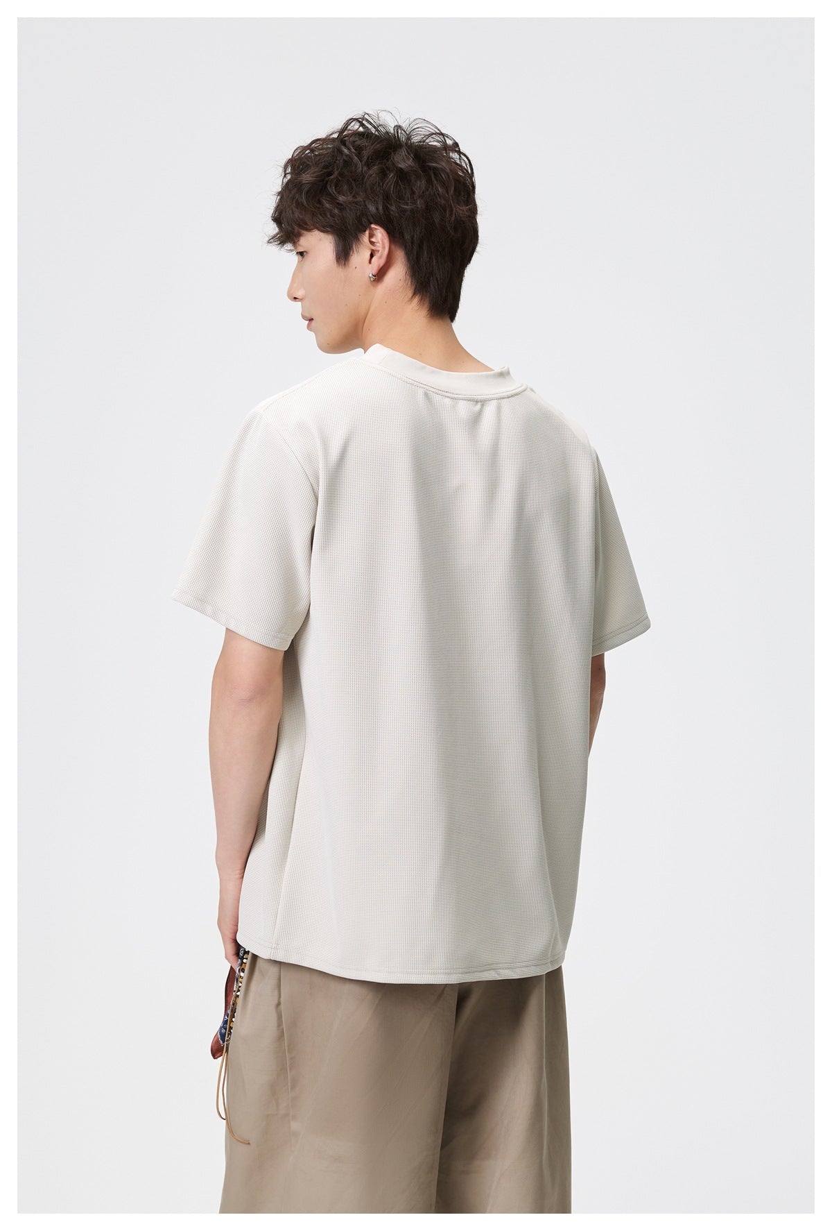 Back view of a model wearing an ivory short-sleeve T-shirt with a plain back.