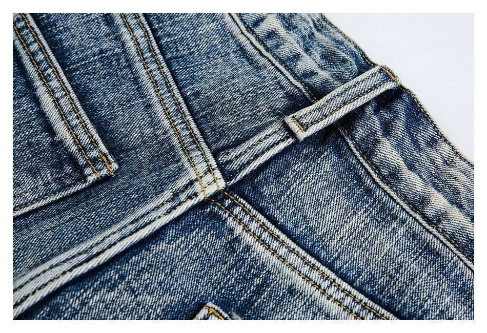 Close-up of blue denim jeans showing the waistband, belt loop, and stitched seams.