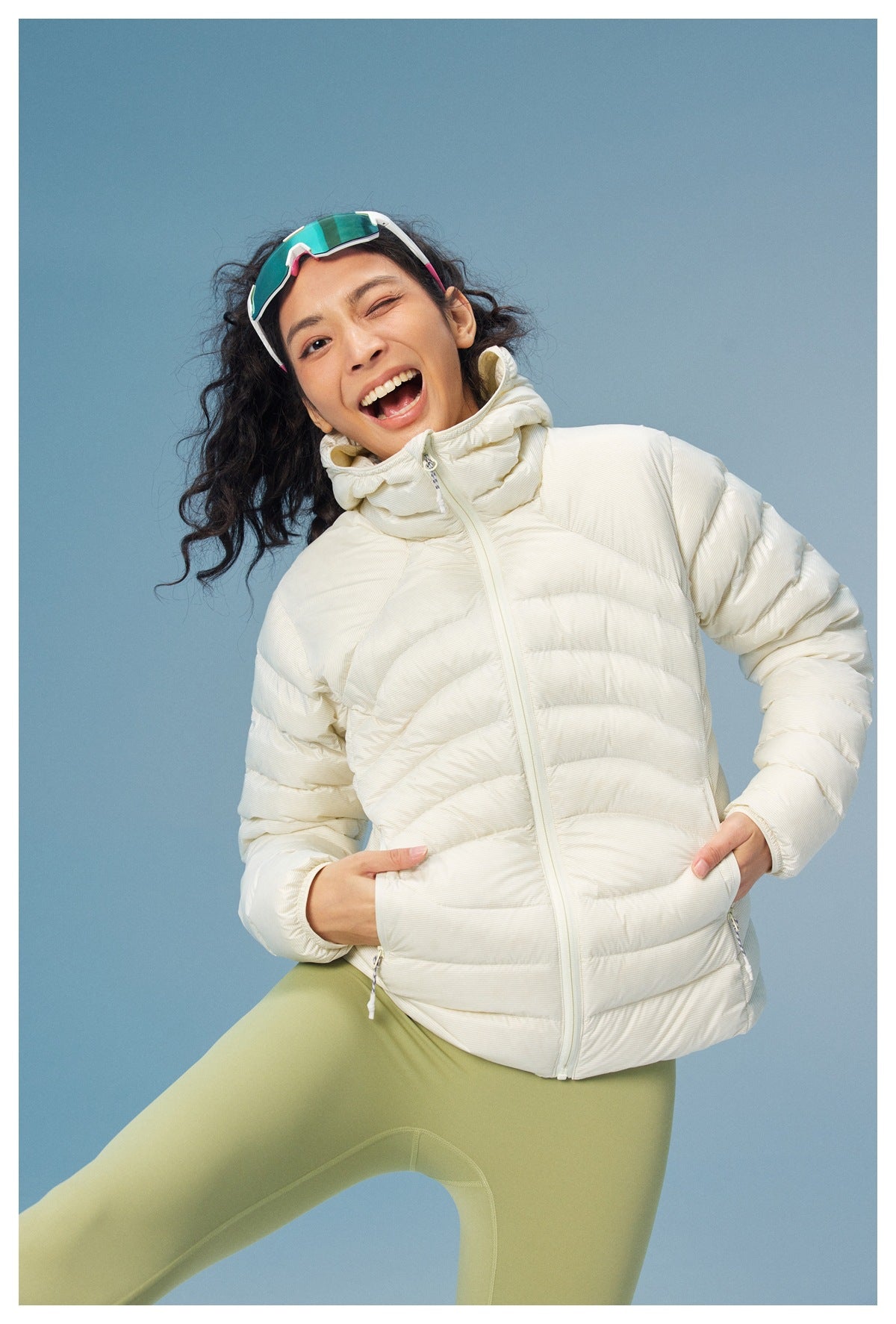 Model wearing a cream quilted puffer jacket with a high collar and front zipper, paired with light green leggings.