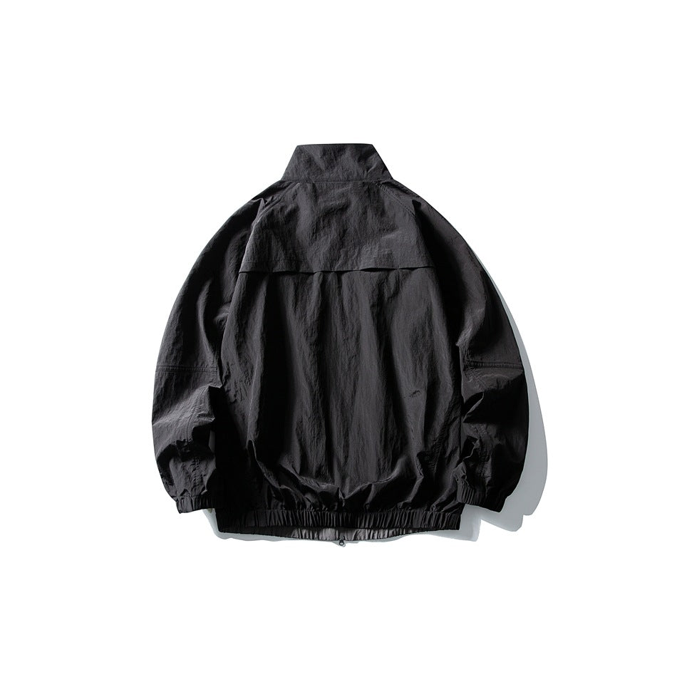Back view of a black jacket with a high collar, back vent flap, and elastic cuffs and hem.