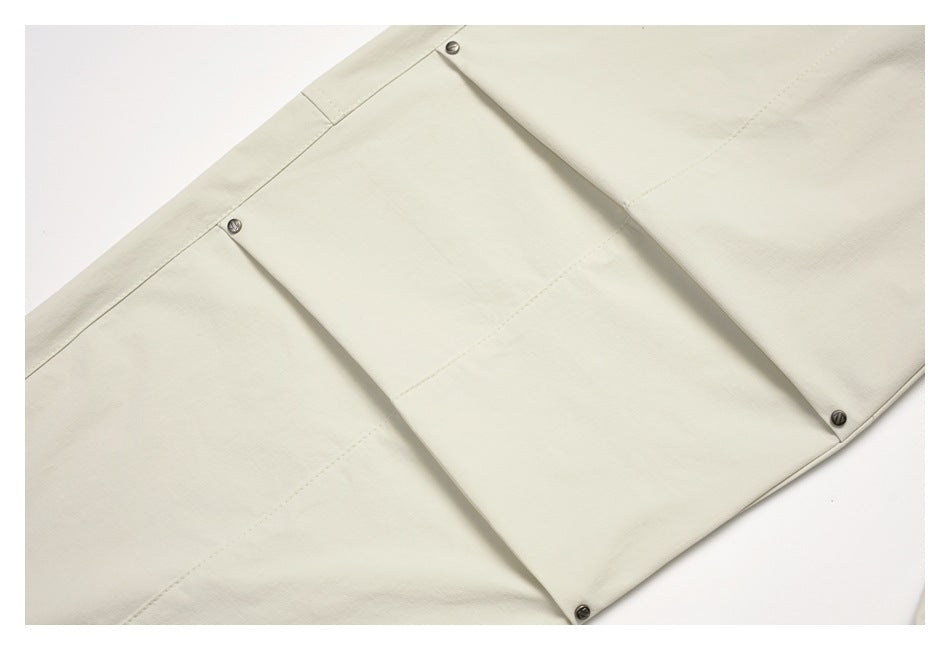 Close-up of an off-white flap pocket secured with metal snaps.