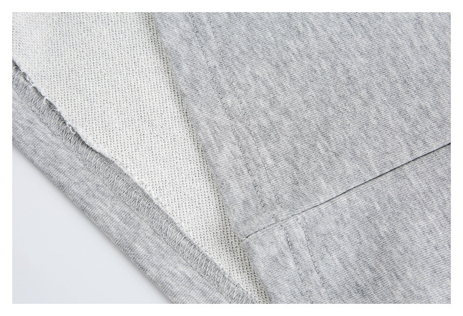 Inside-out close-up of light gray heather sweatpants, showing the reverse knit surface and overlocked seam.