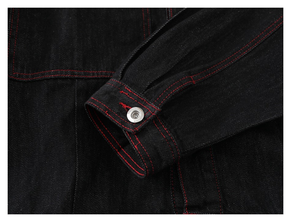 Close-up of a black denim jacket cuff with a silver snap and red stitching.