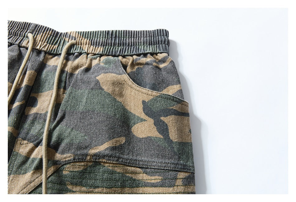 Close-up of camouflage shorts showing the elastic waistband, drawstring, and curved side pocket.