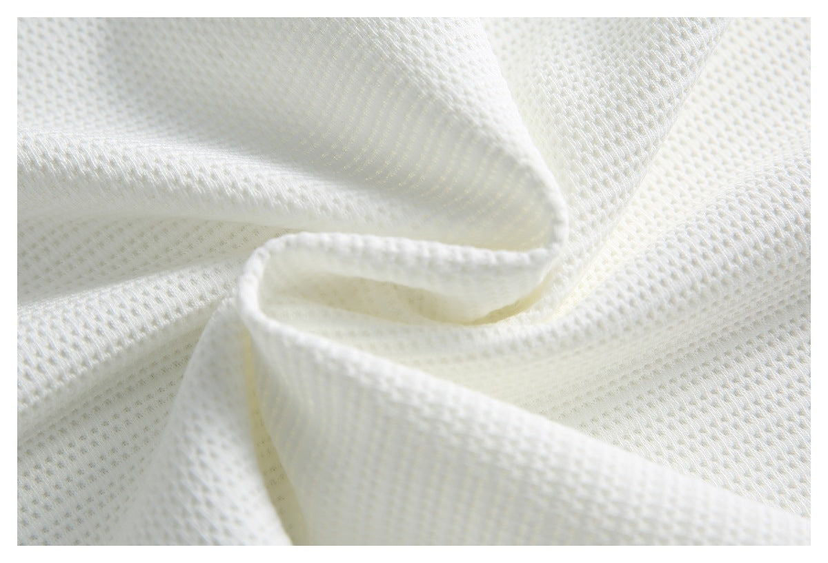 Close-up of folded white knit fabric, highlighting its textured stitches and edge.