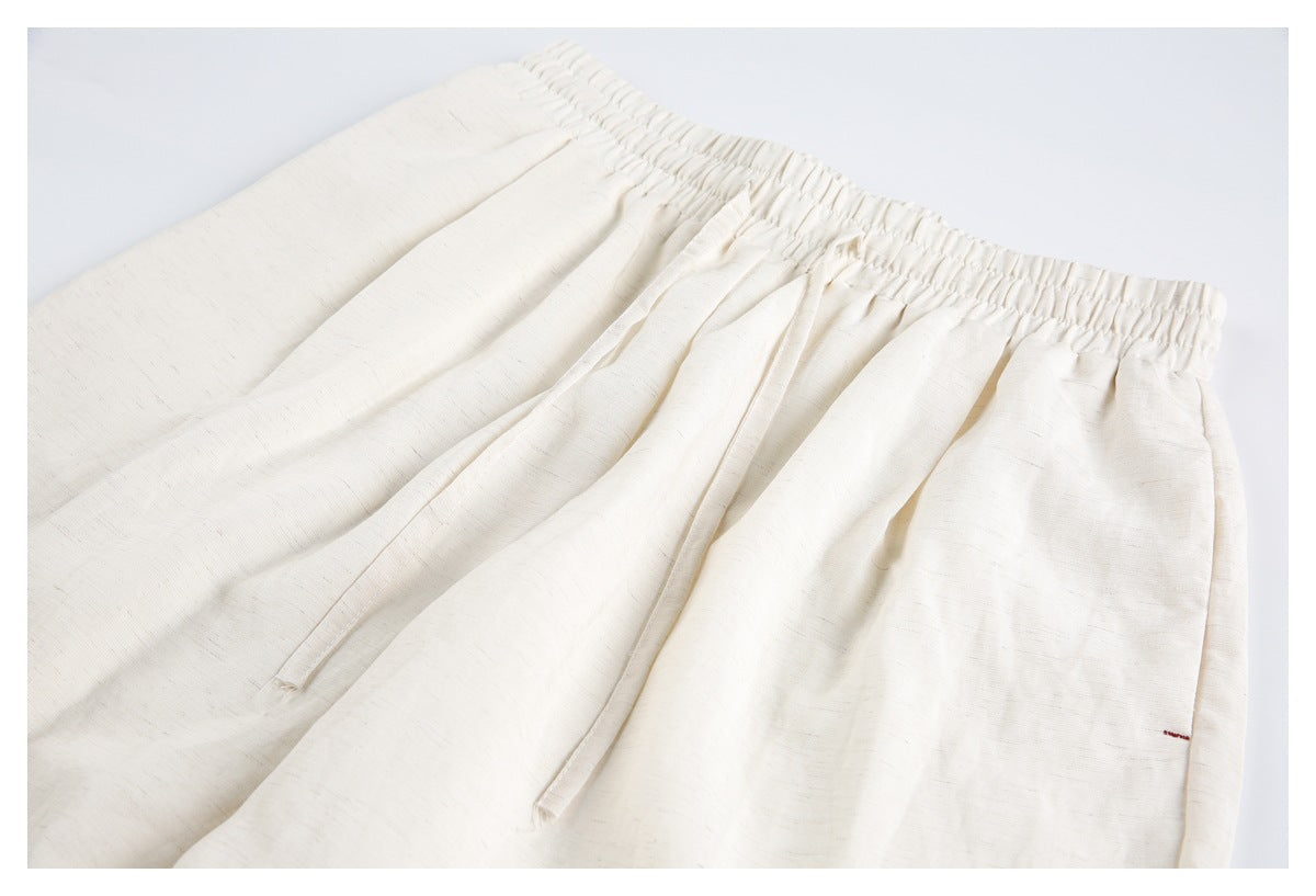 Close-up of ivory shorts showing the gathered elastic waistband, drawstring, and subtle fabric texture.