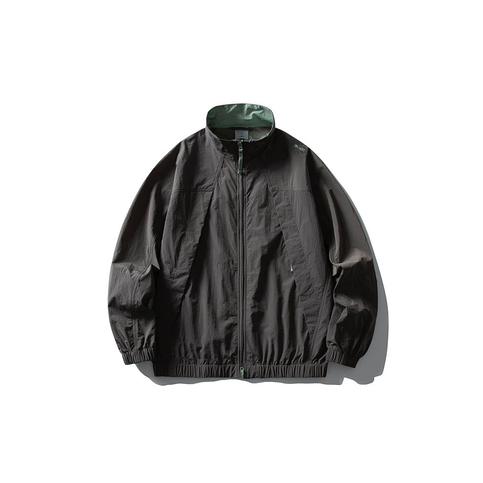 Dark gray zip-up jacket with green inner collar, green zipper pull and elastic hem