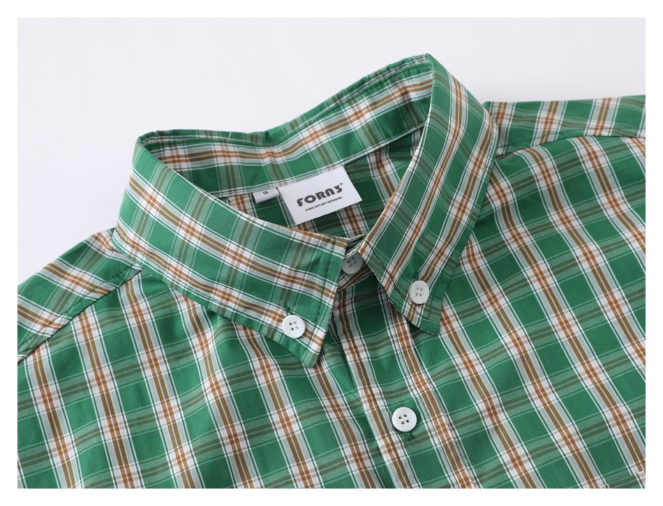 Close-up of a green, brown, and white plaid shirt collar, buttons, and chest.