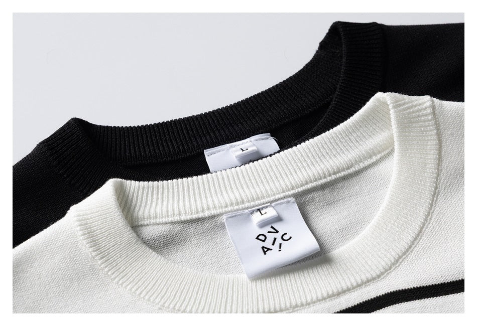 Close-up of overlapping black and white knit crewneck collars with sewn neck labels and a black stripe.