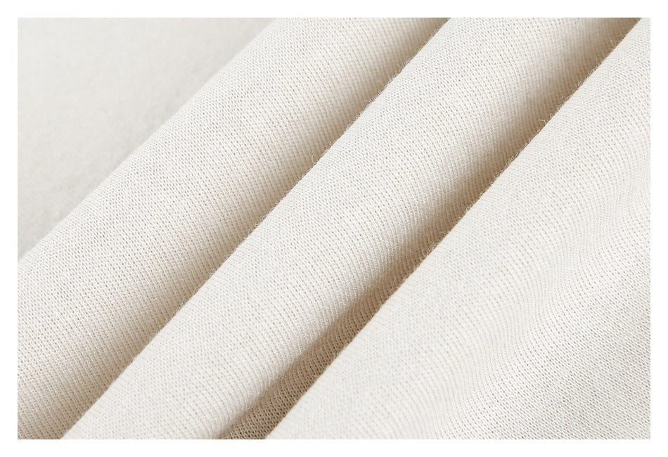 Close-up of off-white fabric folded into ridges, showing its knit texture.