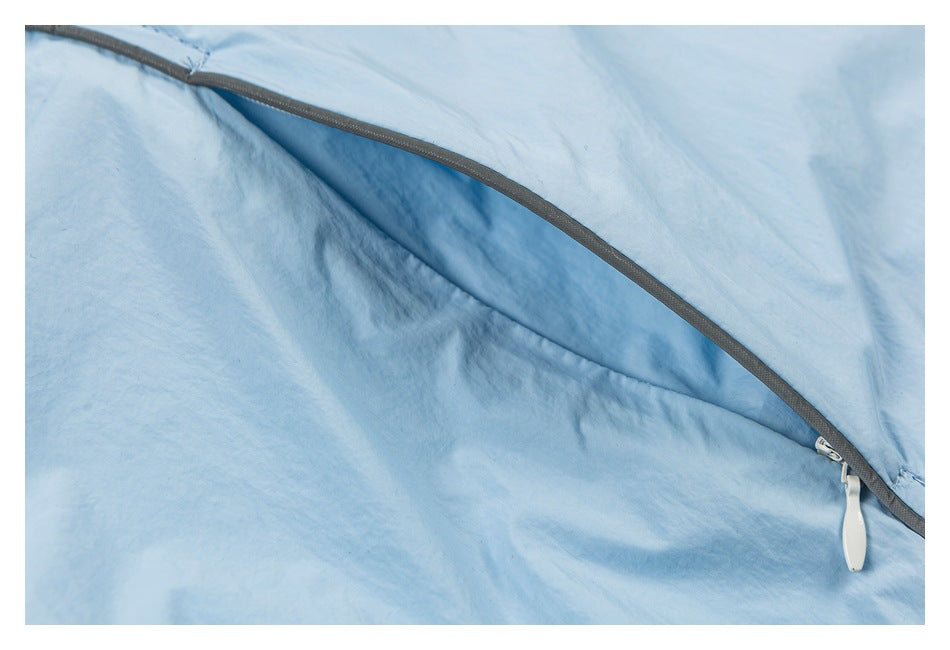 Close-up of a curved gray-trimmed zipper with a white pull on light blue fabric.
