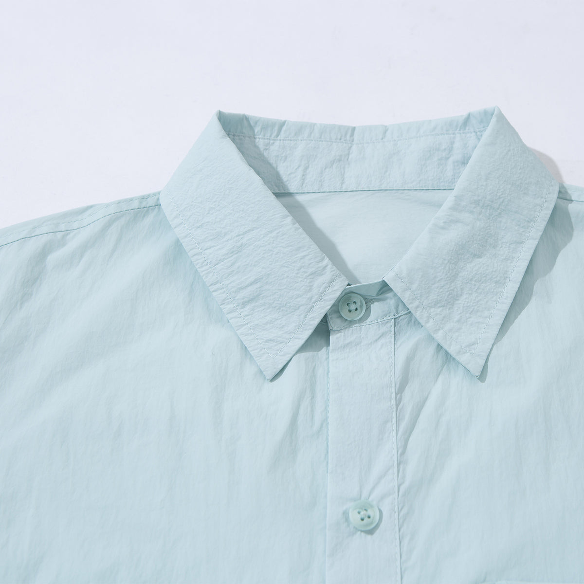 Close-up of a pale aqua button-up shirt collar, top button, and front placket.