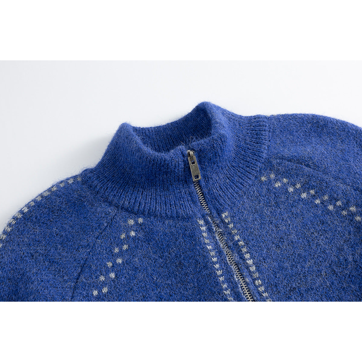 Close-up of a blue knit cardigan's ribbed stand collar, silver zipper, and small light-colored pattern.