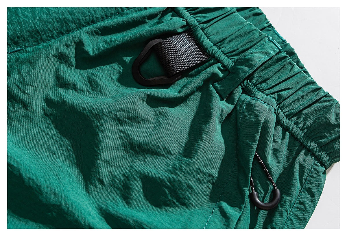 Close-up of teal shorts with an elastic waistband, belt loop and black side attachment loop.
