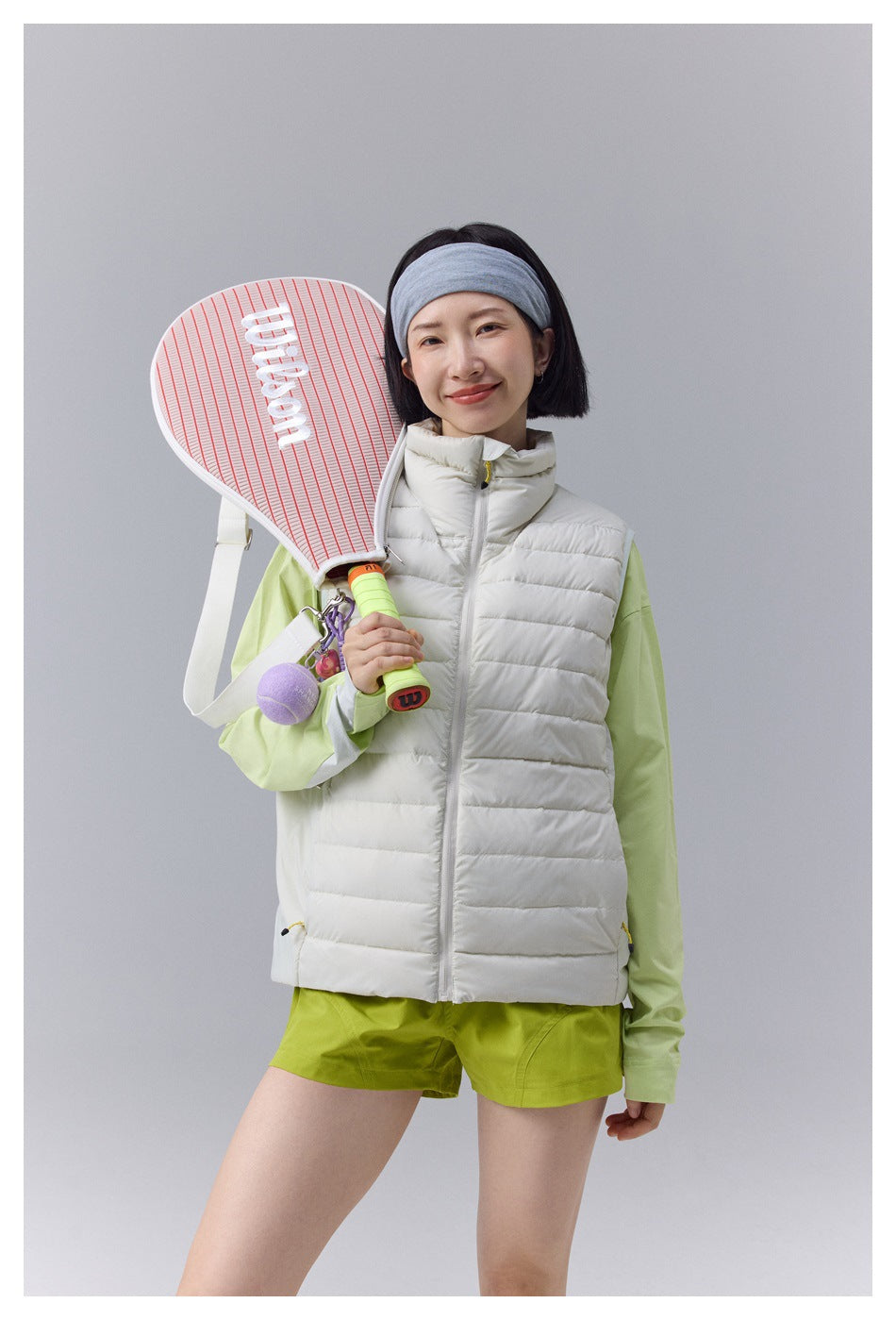 Front view of a woman wearing a white quilted vest with a high collar over a light green top.