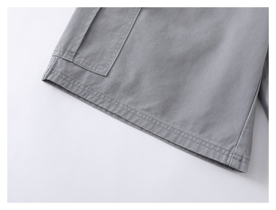 Close-up of gray shorts showing the leg opening, double-stitched hem and edge of a pocket.