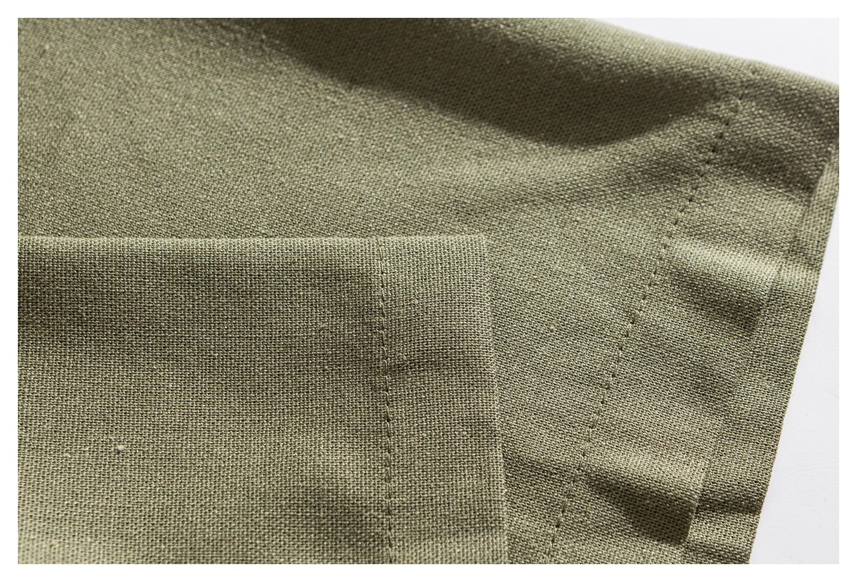Close-up of olive green woven fabric with overlapping folds and visible stitching.