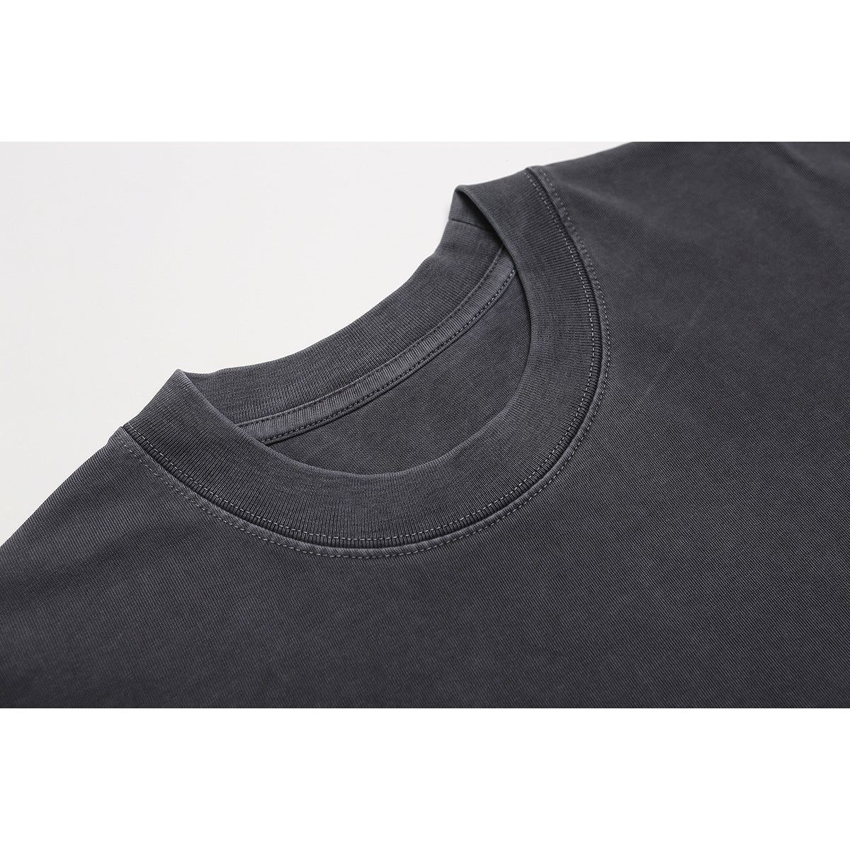 Close-up of a charcoal gray T-shirt's ribbed crew neckline and double stitching.
