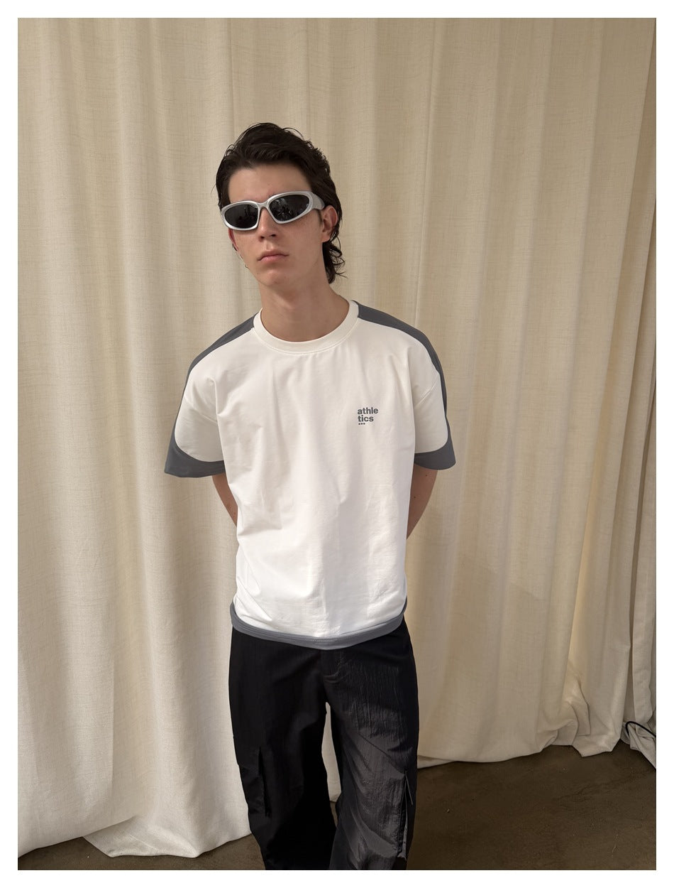 Model wearing a white T-shirt with charcoal-gray shoulder, sleeve, and hem panels, shown from the front.