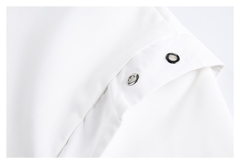 Close-up of two dark metal eyelets set into a white garment tab.