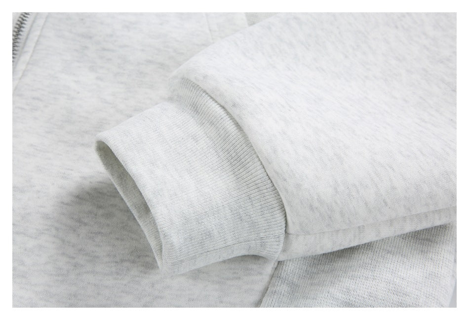 Close-up of a ribbed cuff on a light gray heather sleeve, with part of a zipper visible nearby.