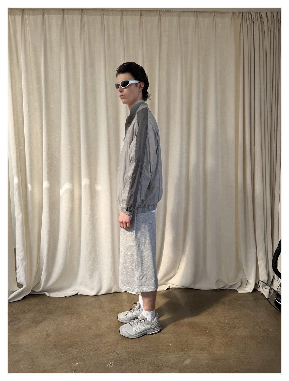 Side view of a model wearing heather gray knee-length shorts with a gray jacket and gray sneakers