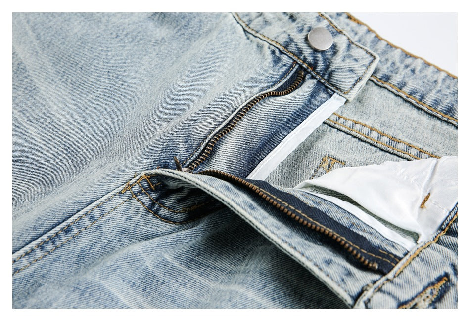Close-up of light-wash jeans with the fly unfastened, exposing the zipper and inner waistband.