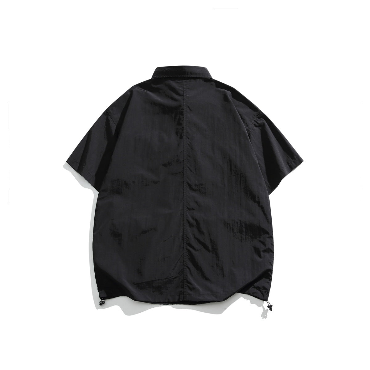 Back view of a black oversized short-sleeve collared shirt with a center seam and adjustable hem cords.