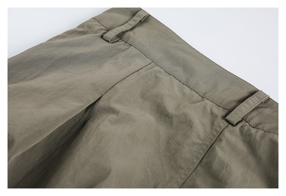 Close-up of olive-gray trouser waistband with belt loops and stitched seams.