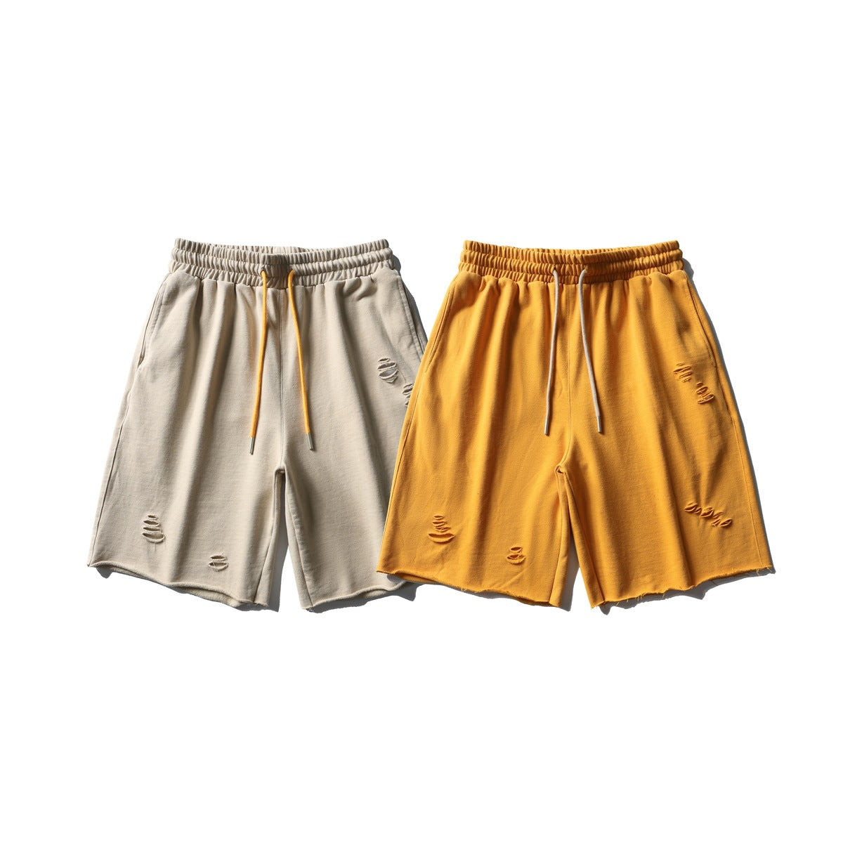 Front view of distressed drawstring shorts in light beige and mustard yellow, shown side by side.