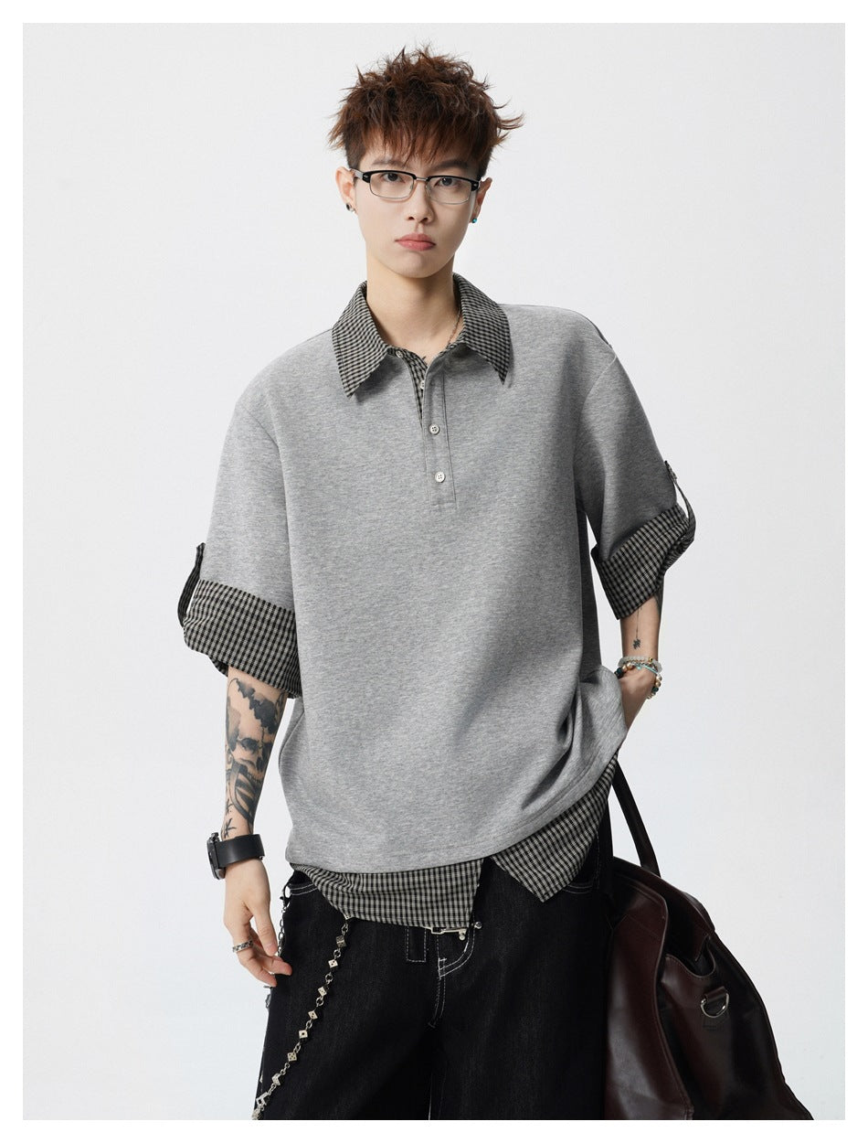 Model wearing an oversized gray polo-style top with checked collar, rolled cuffs, and a checked shirt hem.