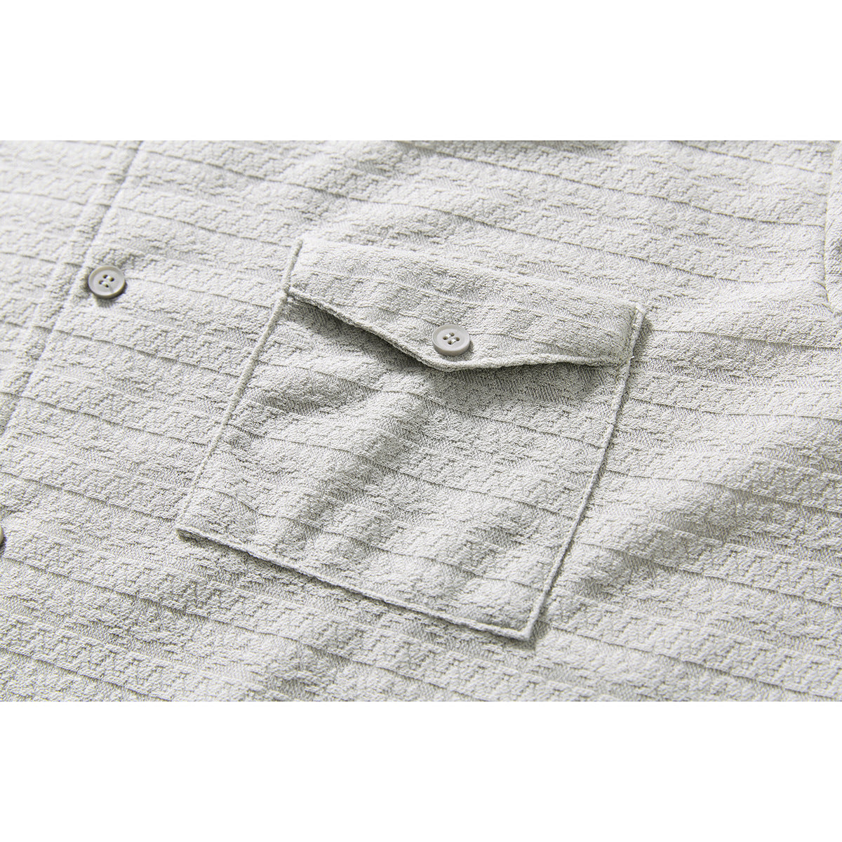 Close-up of a buttoned chest pocket on a light gray shirt with a raised horizontal stripe pattern.